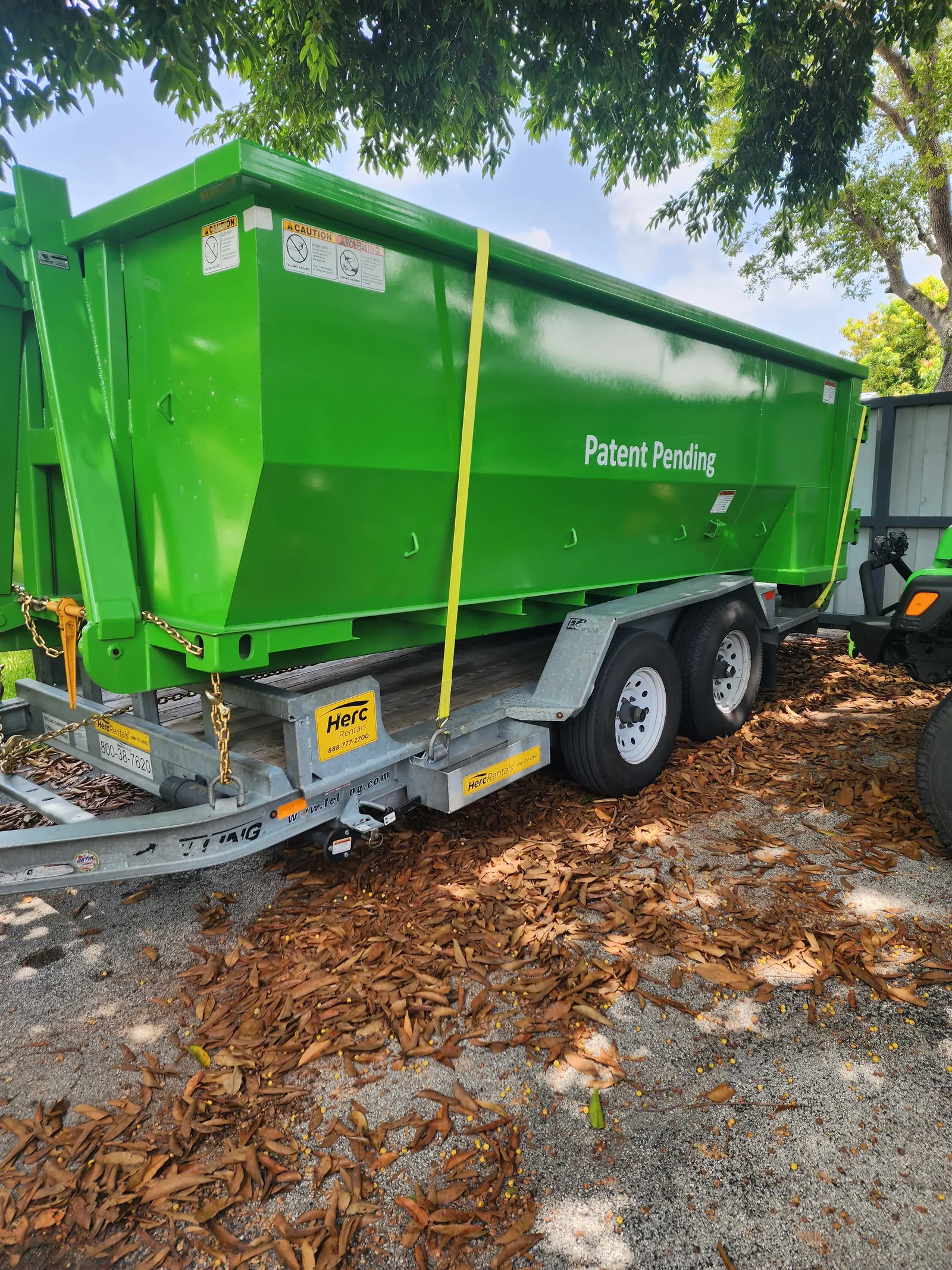 Wheeled dumpster secured on a truck bed at a commercial jobsite