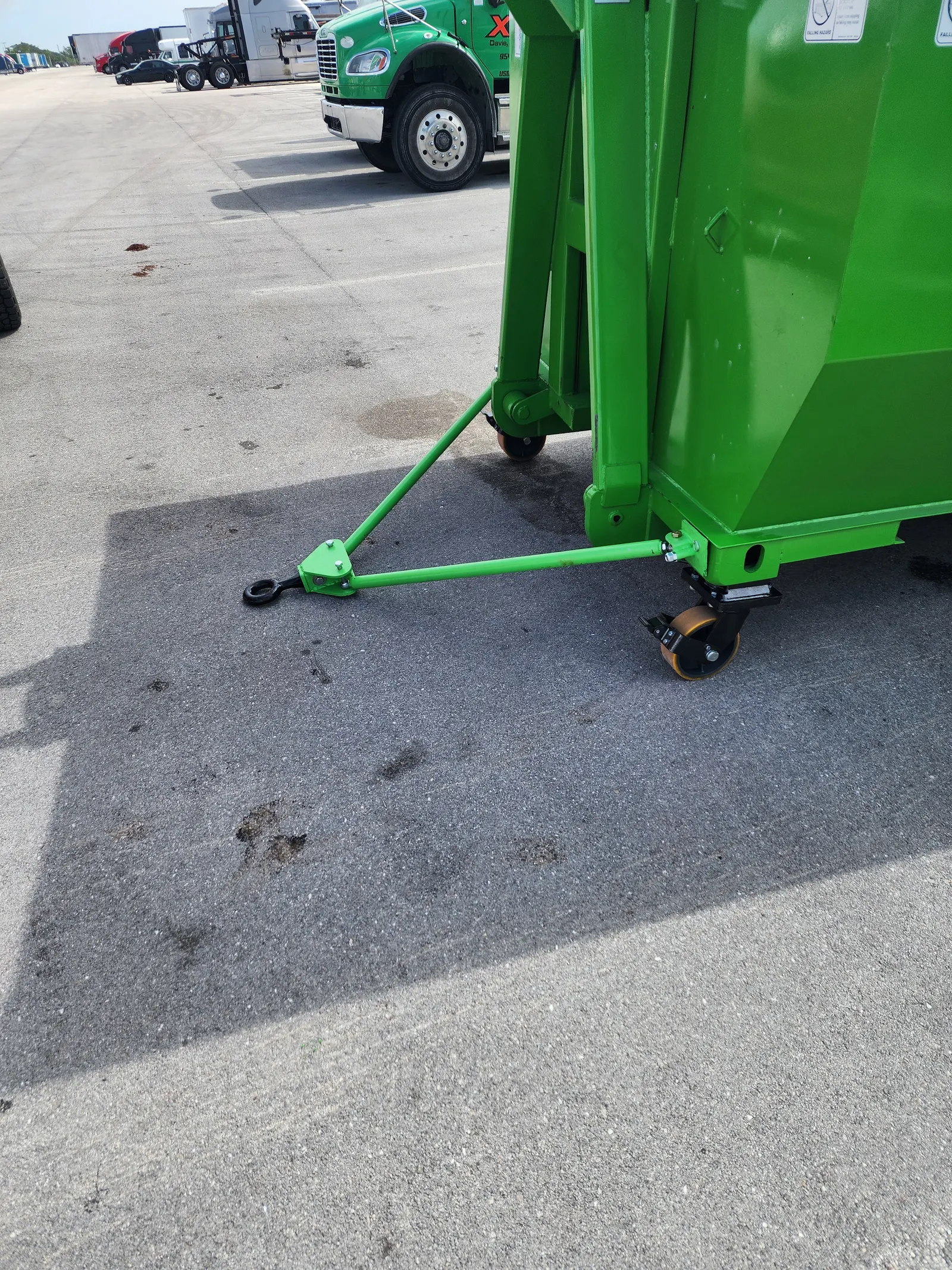 Tow bar attached to the front of a wheeled dumpster